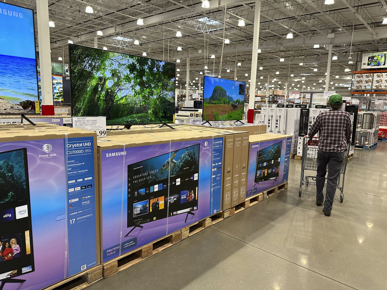 A shopper passes a display of big-screen televisions in a Costco warehouse
