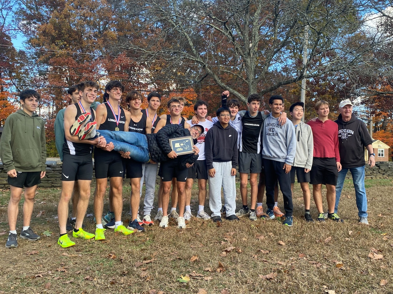 The Longmeadow boys' cross country team celebrates its win by posing with assistant coach Mark Staples on 10/26/25.